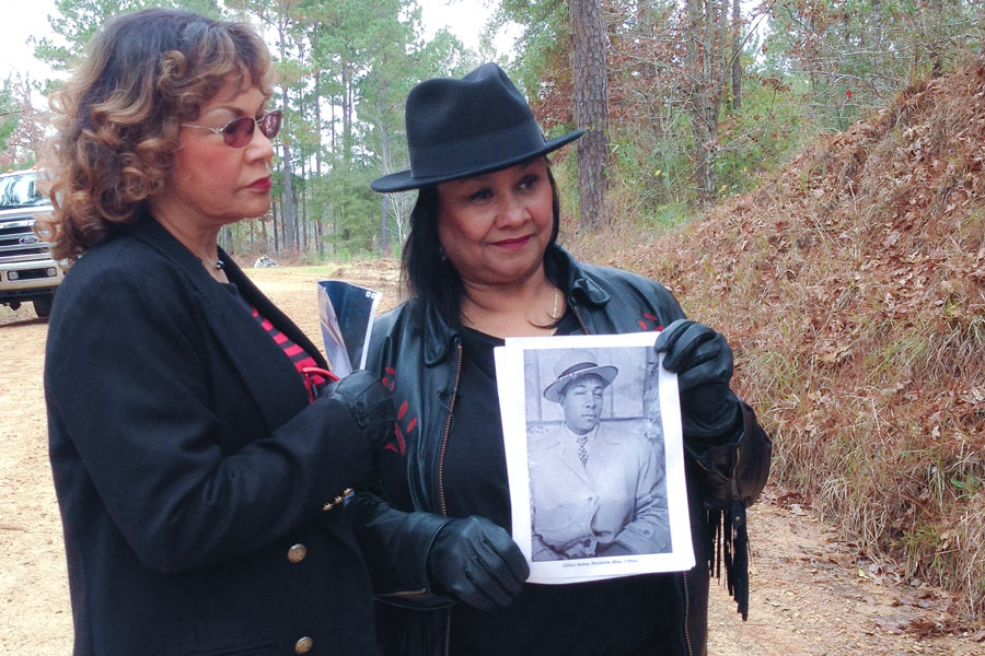 Catherine Walker Jones and Shirley Walker Wright hold a picture of their father, Clifton Walker, and stand on Poor House Road, where he was killed. Photo by Ben Greenberg