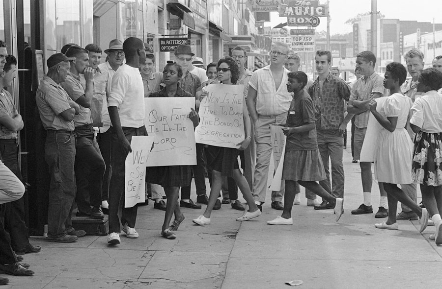 A picketer in front of a Gadsden, Alabama, drugstore turns to answer a heckler during a demonstration, on June 10, 1963. (AP Photo)